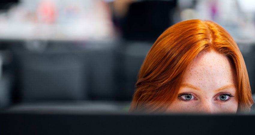 red-haired woman working on computer